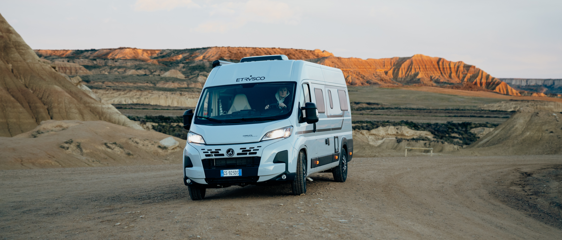 Moderner Etrusco Fiat Campervan Kastenwagen, fährt auf städtischer Straße vor Glasfassade, ideal für urbane Reisen.