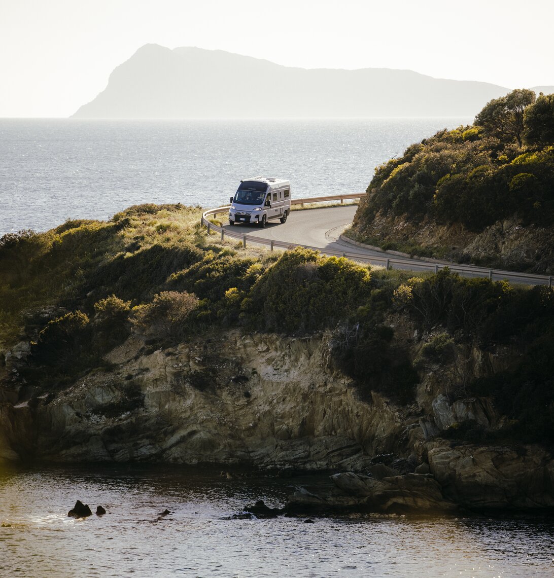 Etrusco Campervan Fiat Plus op cipressenlaan voor toegangspoort, modern ontwerp, omgeven door groen voor stijlvolle kampeerreizen.