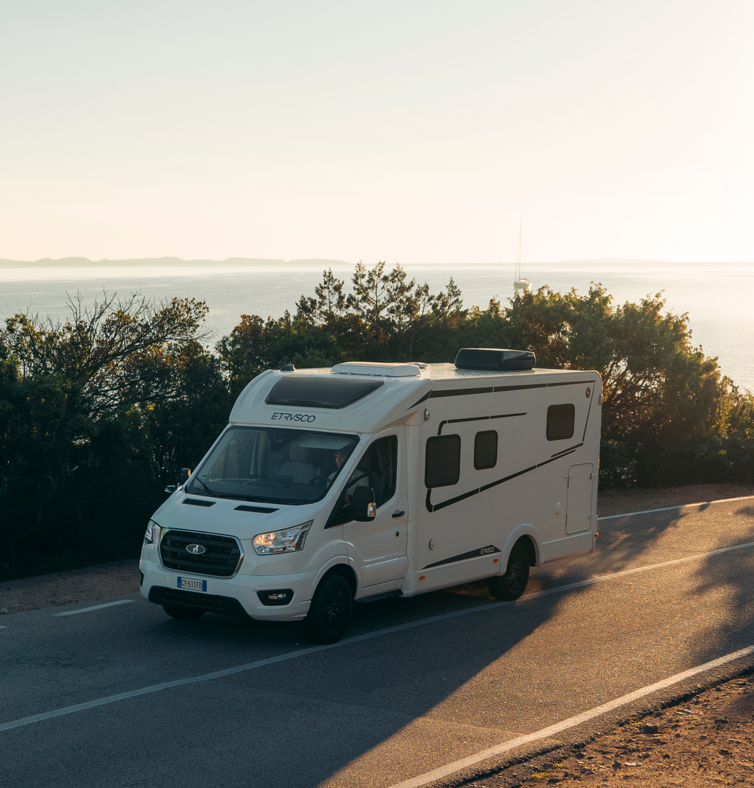 Etrusco Ford varevogn – Smal, delintegreret autocamper på Ford-basis, på vej ad en landevej ved solnedgang.