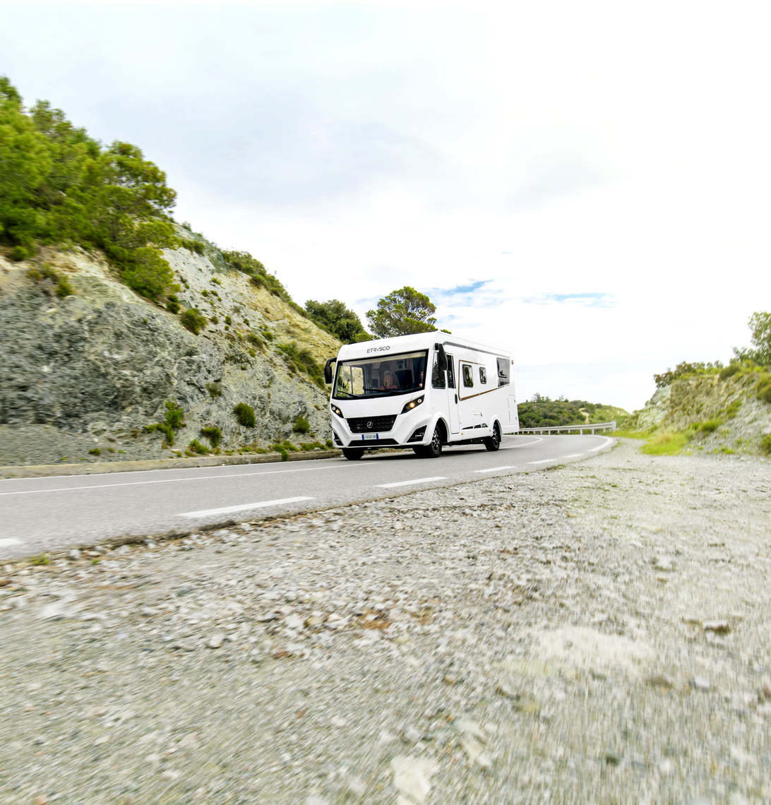 Integriertes Wohnmobil Fiat von Etrusco auf kurviger Straße in bergiger Landschaft – ideal für komfortable Campingreisen und Abenteuer.