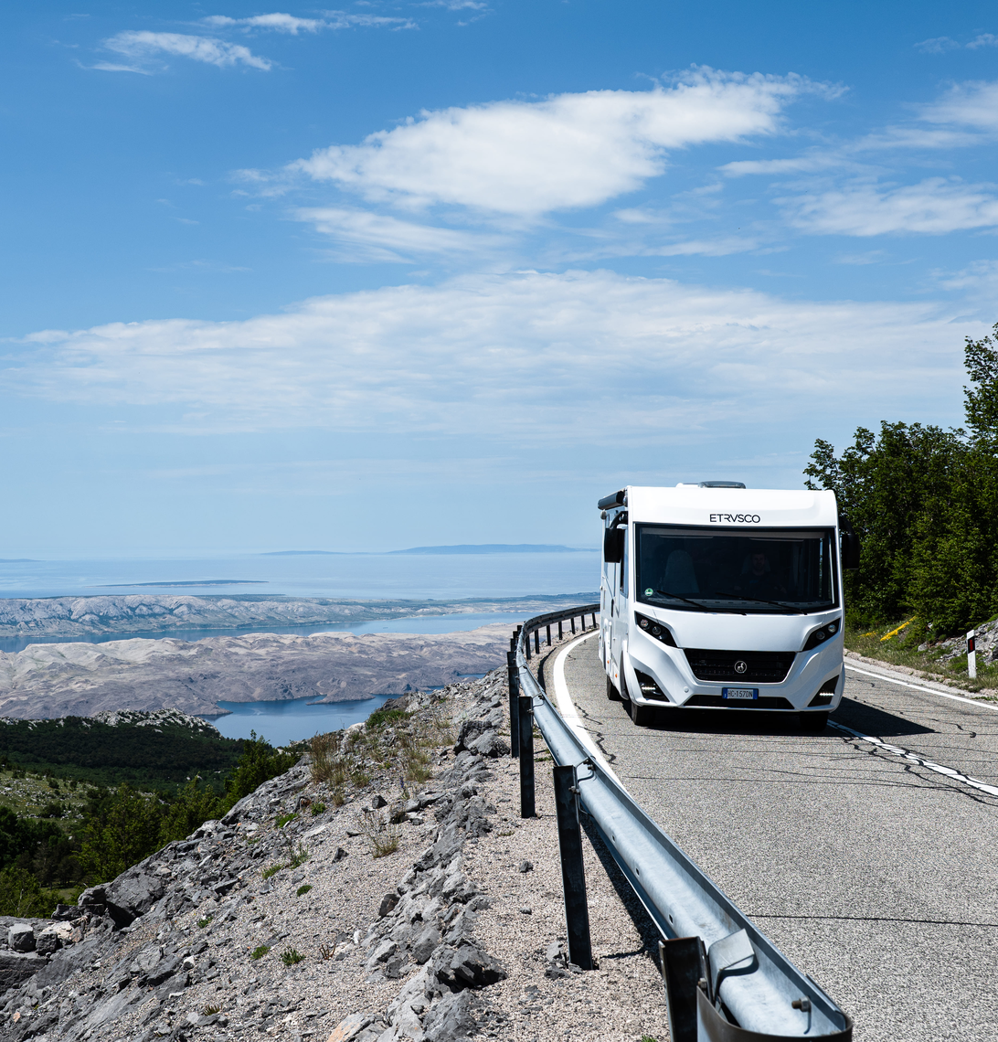 Integriertes Wohnmobil Fiat von Etrusco auf kurviger Straße in bergiger Landschaft – ideal für komfortable Campingreisen und Abenteuer.