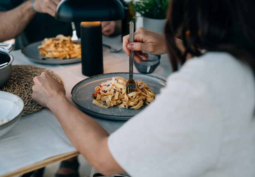 Gemütliche Essensszene in einem Etrusco integrierten Wohnmobil Fiat mit zwei Pizzen und Weingläsern – Genuss und Komfort beim Camping.