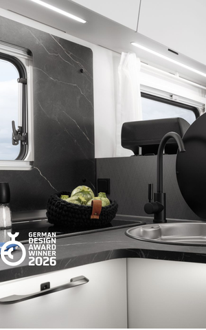 Cocina moderna en la autocaravana Etrusco con tabla de cortar, melón, hierbas y un hornillo de gas de dos fuegos, ideal para acampar.